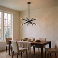 12-Light Stilnovo Chandelier – Handmade Raw Brass Ceiling Lamp in Antique Black, shown installed in a dining room