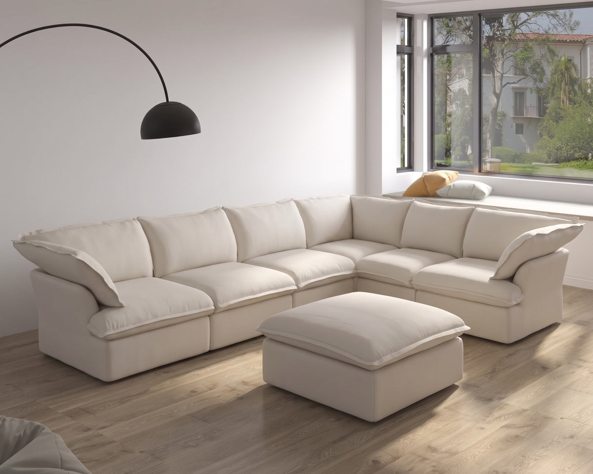 Cloud Sectional in cream, arranged along a sunlit living room wall with a black arc floor lamp and a hexagonal wood coffee table