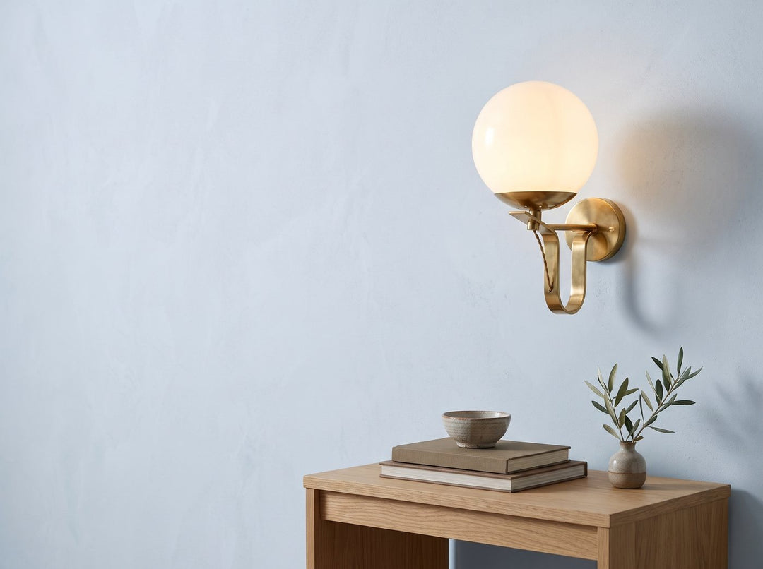 Brass globe wall sconce above an oak console